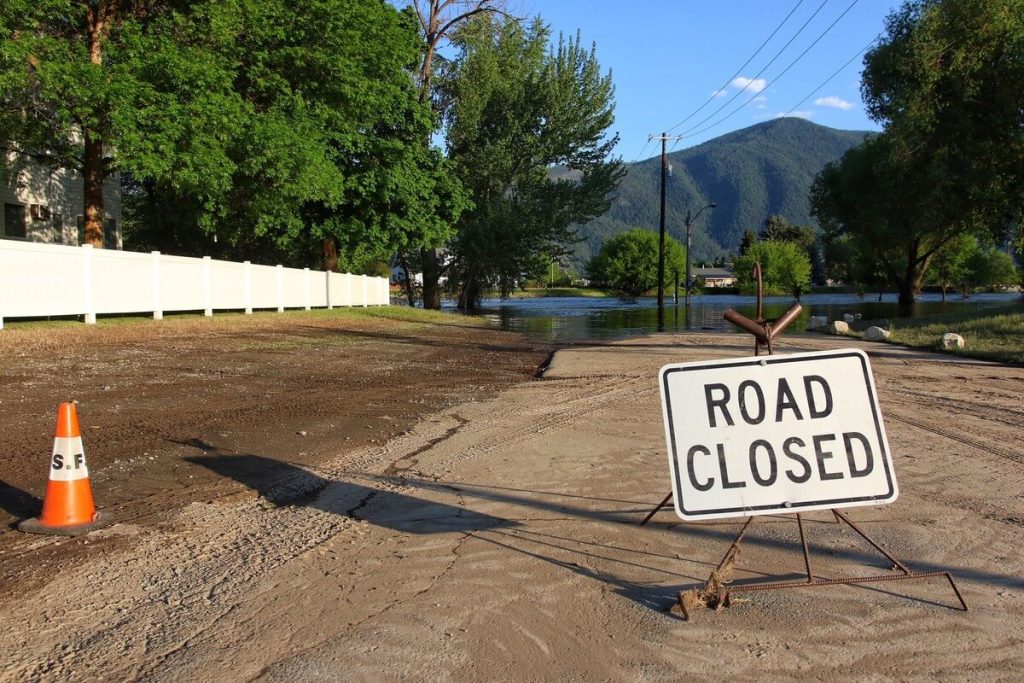 Flood damaged road with a road closed sign.