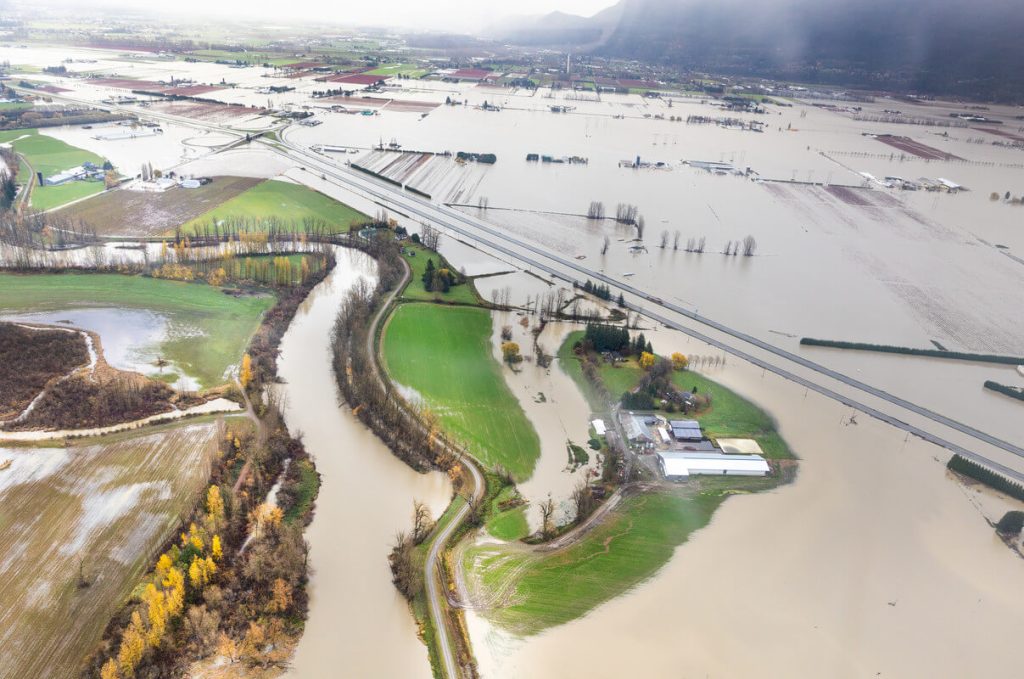 Aerial view of Fraser Valley farmland flooded with brown water.