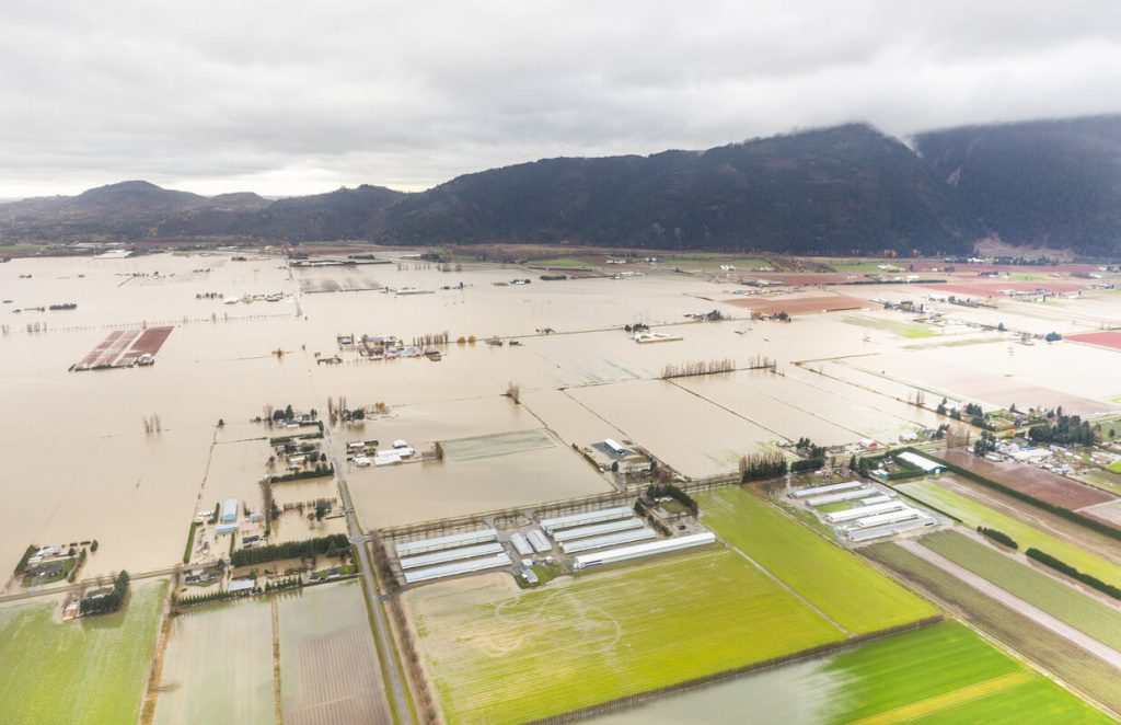 Aerial view of Fraser Valley farmland flooded with brown water.