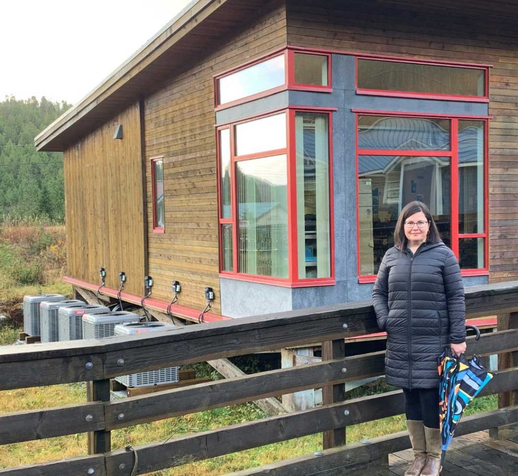 Person stands in from of a building with installed heat pumps.