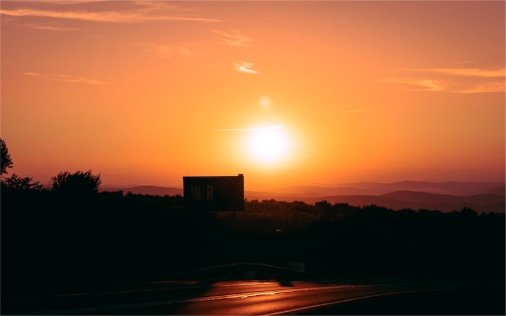 Hazy orange sunset over buildings and trees.